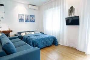 A modern bedroom with a bed, a sofa, and a TV. - Unique property: 120 square meters - 150 meters from the beach - garage (Lido di Jesolo)