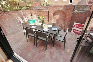 A brick patio with a table set for four, a 'Public Bites' sign, and a 'Do Not Enter' sign. - Stunning Georgetown Townhouse, Rooftop Oasis (Washington)