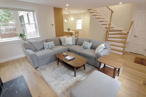 A modern living room with a grey sectional sofa, a wooden coffee table, and a small side table.