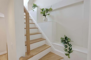 A staircase with wooden steps and white walls, featuring two potted plants on the landing. - Stunning Georgetown Townhouse, Rooftop Oasis (Washington)