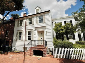 A two-story white building with a brick entrance and a white picket fence.