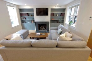 A living room with a fireplace, sofa, coffee table, and bookshelves.
