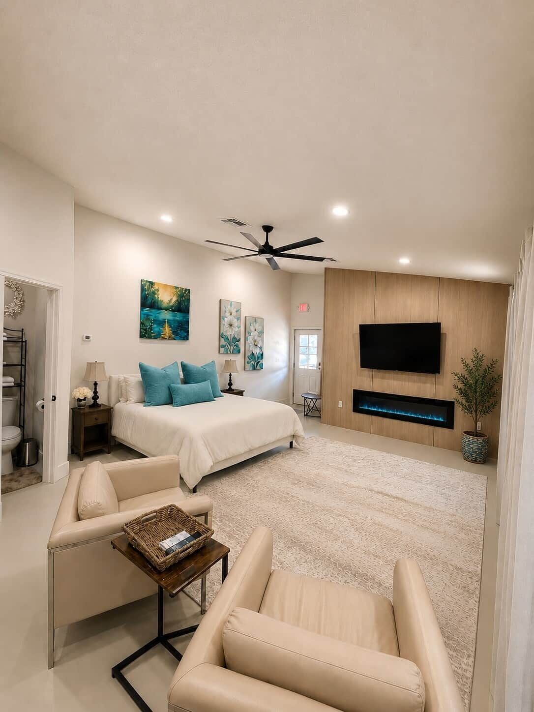 A modern bedroom with a large bed, a TV, and a ceiling fan.