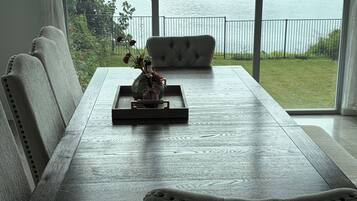 A dining area with a view of a lake, a sofa, and a table with a decorative item.