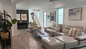 Ein modernes Wohnzimmer mit einem Ecksofa, einem Couchtisch und einer Treppe, die zu einer oberen Etage führt.