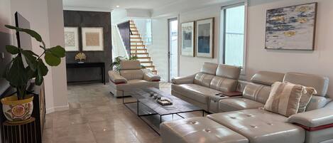 Una sala de estar moderna con un sofá modular, una mesa de centro y una escalera que sube a un piso superior.