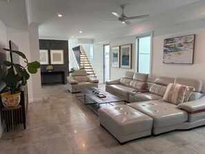 A modern living room with a sectional sofa, a coffee table, and a staircase leading to an upper floor.
