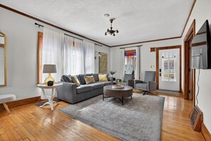 A living room with a grey sofa, a round coffee table, a lamp, and a television. - Walk to Mayo Clinic! Luxury Furnished 4-bedroom house. Perfect for families (Rochester)