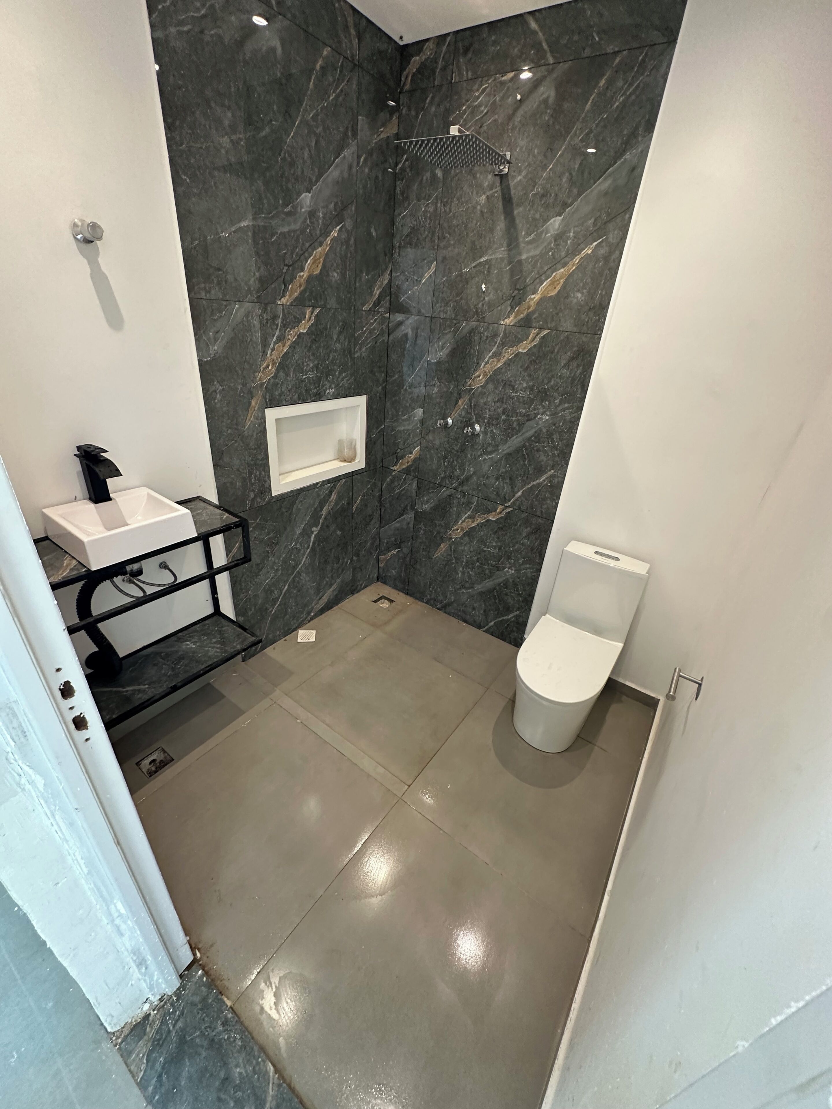 Une salle de bain moderne équipée d’une douche, de toilettes et d’un lavabo.