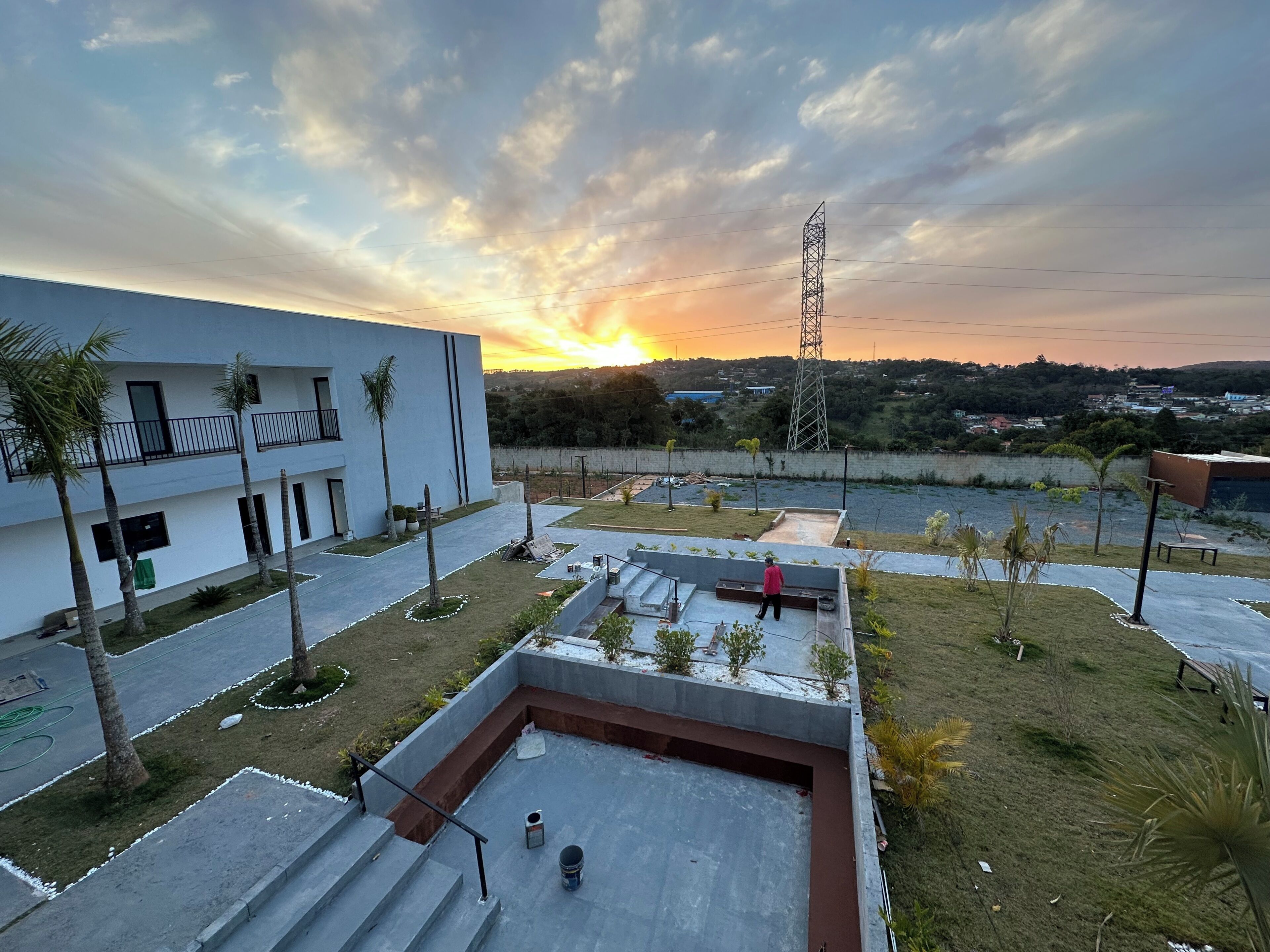 A courtyard with a building, a person walking, and a sunset.