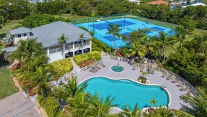 Un resort con piscina, canchas de tenis y un edificio con balcón.