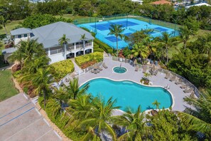 Ein Resort mit Schwimmbad, Tennisplätzen und einem Gebäude mit Balkon.