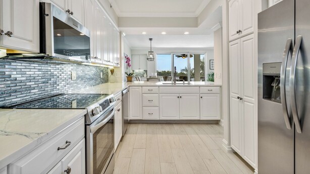 Una cocina moderna con armarios blancos, un refrigerador de acero inoxidable y salpicadero de azulejos.