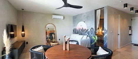 A dining area with a round wooden table, black upholstered chairs, and a ceiling fan.
