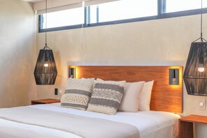 A modern bedroom with a large bed, two bedside tables, a wooden headboard, and hanging pendant lights. - Modern 2BR Retreat in Parques Zama w/ Private Pool (Tulum)