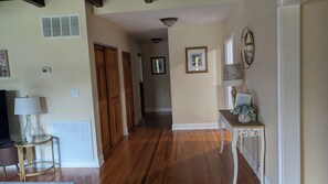 A hallway with wooden flooring, a round table with a lamp, and a wall-mounted picture frame.