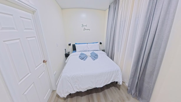 Ein Hotelzimmer mit Bett, Nachttisch, Wandleuchte und Tür.
