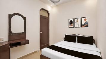 A bedroom with a bed, a dresser, a door, and three framed artworks on the wall.