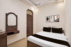 Une chambre à coucher avec un lit, une commode, une porte et trois œuvres d’art encadrées accrochées au mur.