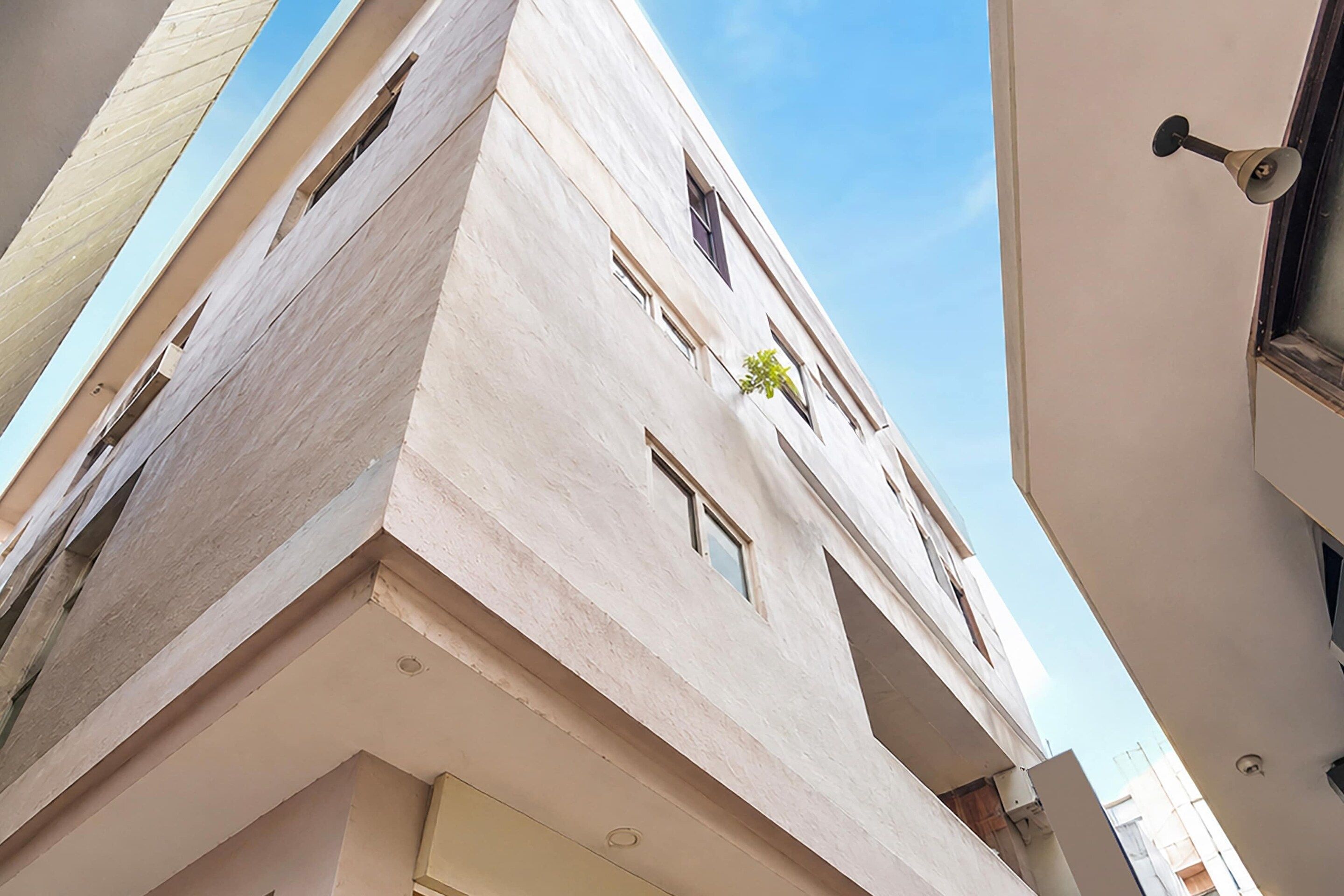 A multi-story building with a flat facade, rectangular windows, and a visible balcony.
