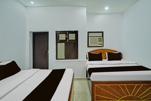 Une chambre d’hôtel avec deux lits, une porte, une fenêtre et une radio fixée au mur.