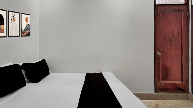 Un dormitorio con cama, almohadas, una puerta y decoración en la pared.