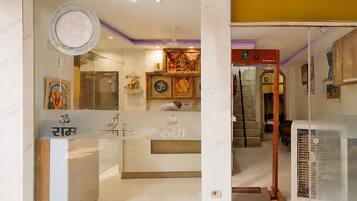 A hotel lobby with a reception desk, a staircase, and a wall with religious symbols.