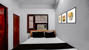Un dormitorio con una cama, un ventanal, un radiador y tres cuadros en la pared.