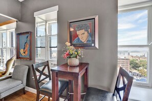 Una sala de estar moderna con comedor, ventanas amplias y obras de arte en las paredes.