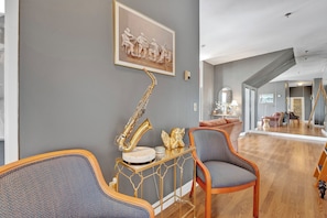 Ein modernes Wohnzimmer mit grauer Wand, einem gerahmten Bild, einem Saxophon und einer goldenen Engelstatue.