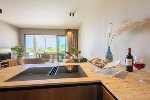 A modern kitchen with a built-in stove, a dining area with a table and chairs, and a view of the outdoors. - Private Pool Escape - Luminara at The Reef (Willemstad)
