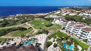 Ein Resort mit mehreren Schwimmbecken, einem Golfplatz und Blick auf den Ozean.