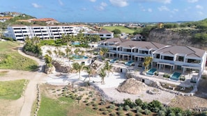 Ein Resort mit mehreren Gebäuden, einem Poolbereich und Blick auf die umliegende Landschaft.