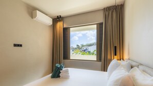 Une chambre d’hôtel avec un lit, une fenêtre avec des rideaux, un appareil de climatisation et une vue sur l’extérieur.