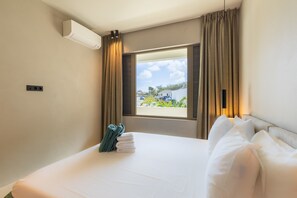 Ein Hotelzimmer mit Bett, einem Fenster mit Vorhängen, einer Klimaanlage und Blick nach draußen.