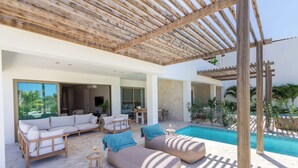 Un espace de vie extérieur moderne, doté d’une piscine, d’une pergola en bois et de sièges confortables.
