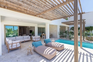 Ein moderner Außenbereich mit Pool, einer Holzpergola und bequemen Sitzgelegenheiten.