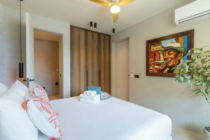 Une chambre d’hôtel avec un lit, un tableau, un ventilateur de plafond et un appareil de climatisation.