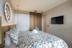 Ein Hotelzimmer mit einem Bett, einem flachbildfernseher an der Wand, einer Tür und einer Deckenleuchte.