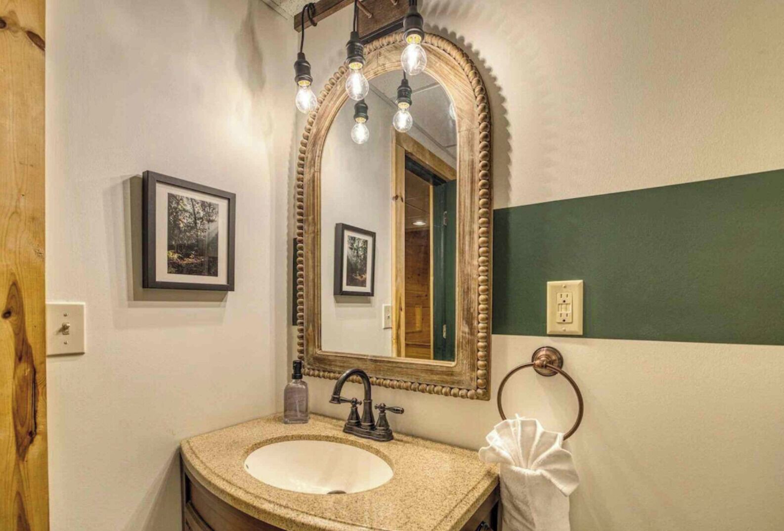 A bathroom with a freestanding sink, a large mirror with a decorative frame, and a towel ring.