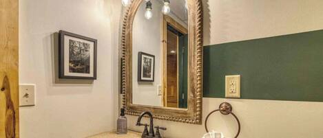 A bathroom with a freestanding sink, a large mirror with a decorative frame, and a towel ring.