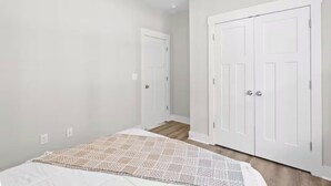 A bedroom with a bed, a ceiling fan, and white double doors.