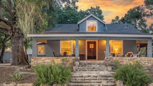 A two-story house with a stone staircase leading to the front door, surrounded by a stone wall and greenery. - Dunning Ranch Guest Buyout by Avantstay 40-acre Vineyard Estate + Spa Tub BBQ + Private Decks (Paso Robles)