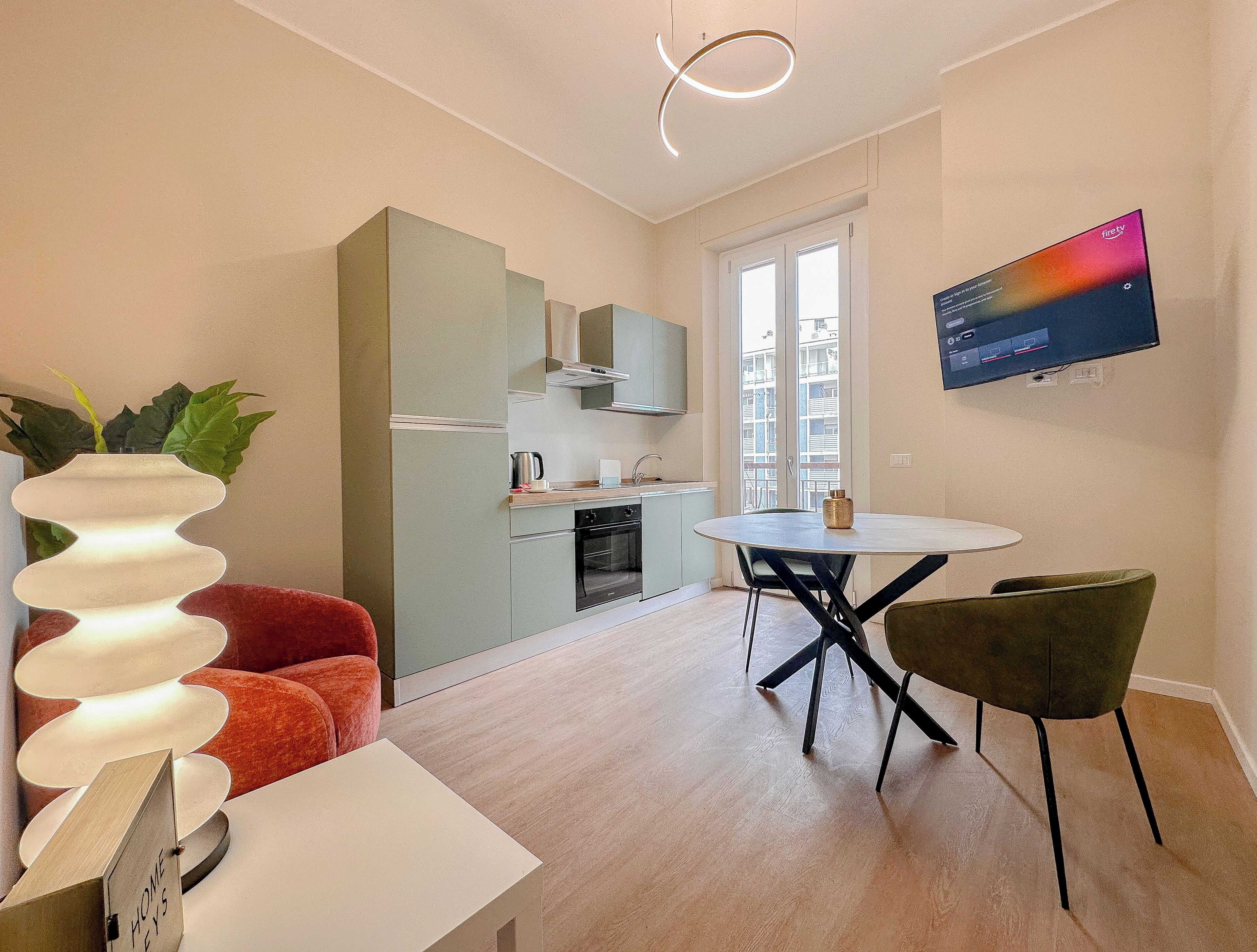 Un apartamento moderno con cocina, comedor y televisor montado en la pared.