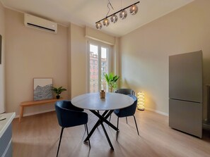A modern kitchen with a dining table, chairs, a refrigerator, and a window with a view of buildings. - Flatsharing - Gioia Bordeaux suite - 1 bedroom (Milan)