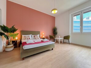 A hotel room with a bed, bedside lamps, a small table, chairs, and a large window. - Flatsharing - Gioia Bordeaux suite - 1 bedroom (Milan)
