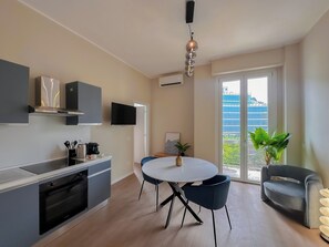 Eine moderne Küche mit Essbereich, einem Flachbildfernseher und Blick auf eine Stadtlandschaft durch ein großes Fenster.