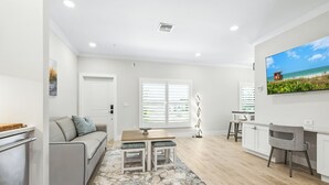 Uma sala de estar moderna com sofá, mesa de centro e televisão na parede.