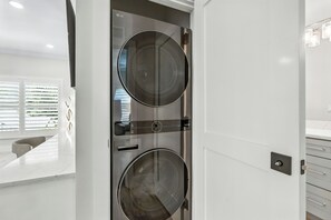 Ein modernes, minimalistisches Badezimmer mit einer Waschmaschine mit Doppeltür und einem eleganten, weißen Waschtisch.