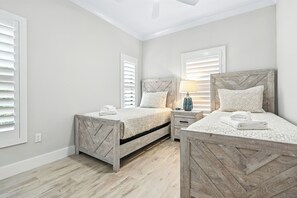 Ein Schlafzimmer mit zwei Betten, einem Nachttisch, einer Lampe und einem Deckenventilator.